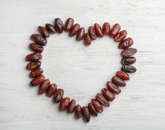 Frame made of sweet dried date fruits on wooden background, top view with space for text