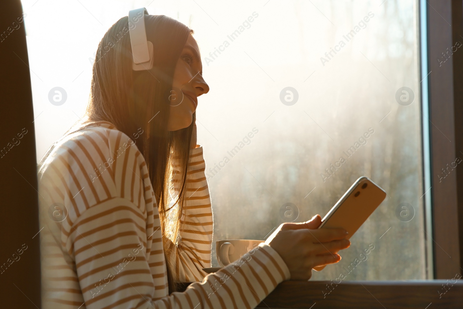 Photo of Woman listening to audiobook at table in cafe