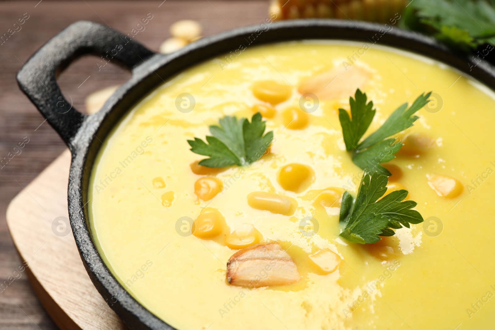 Photo of Delicious creamy corn soup on wooden table, closeup