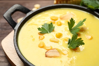 Photo of Delicious creamy corn soup on wooden table, closeup