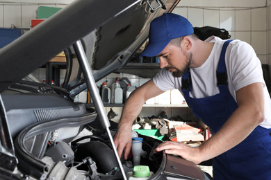 Professional auto mechanic fixing modern car in service center