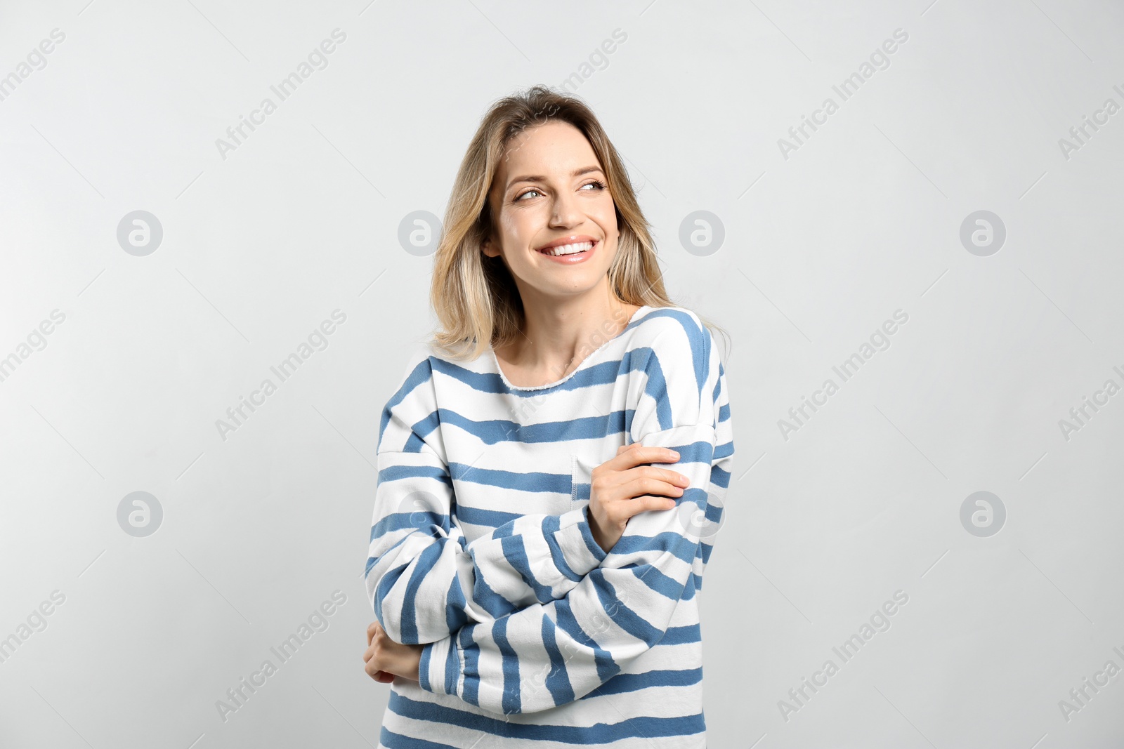 Photo of Portrait of happy young woman with beautiful blonde hair and charming smile on light background