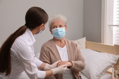 Doctor taking care of senior woman with protective mask at nursing home