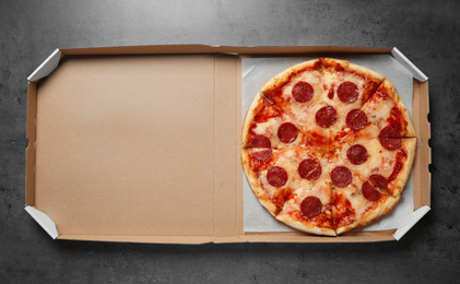 Hot delicious pepperoni pizza in cardboard box on grey table, top view