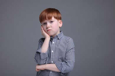 Portrait of sad little boy on grey background