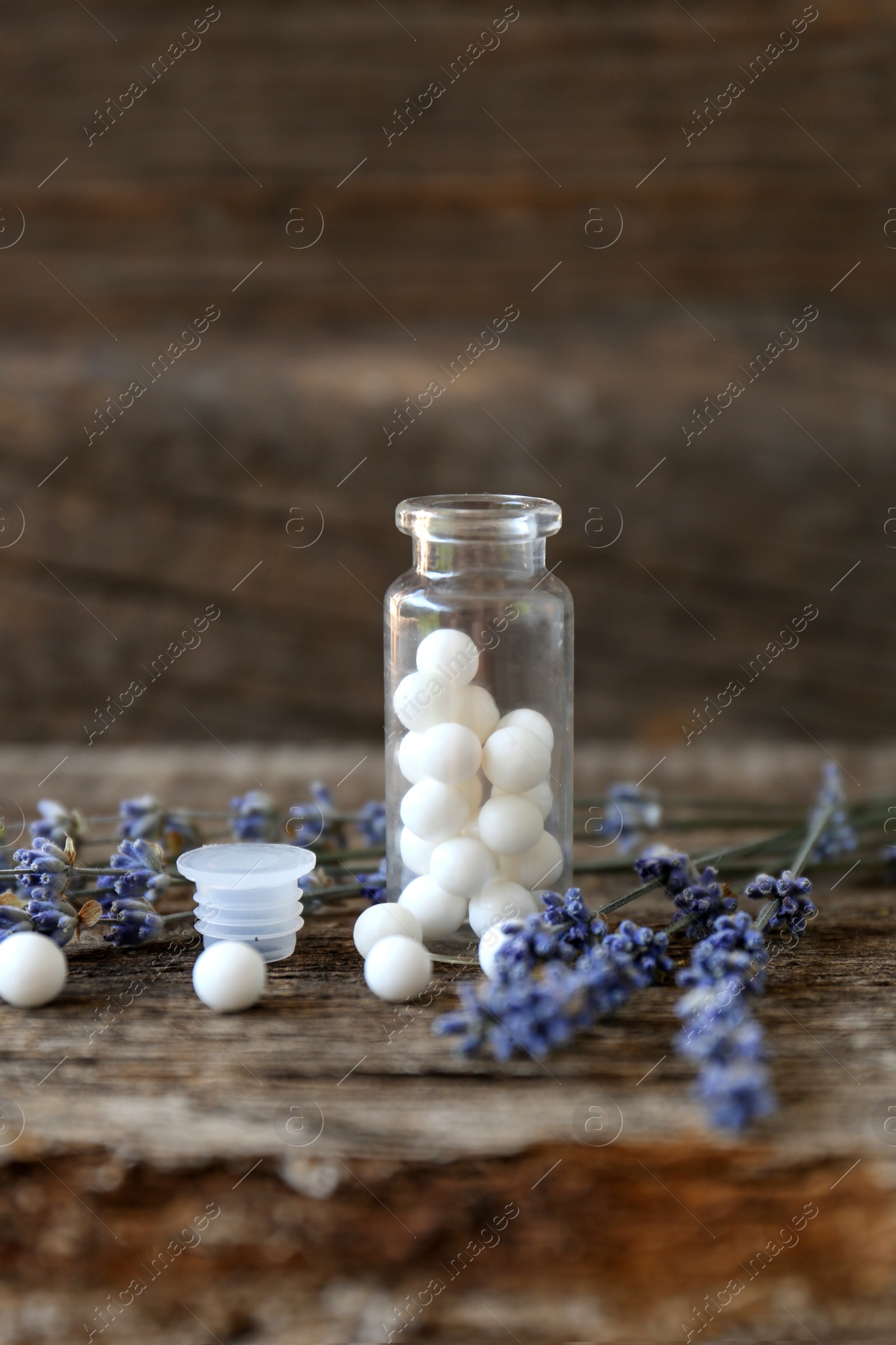 Photo of Bottle with homeopathic remedy and lavender flowers on wooden table