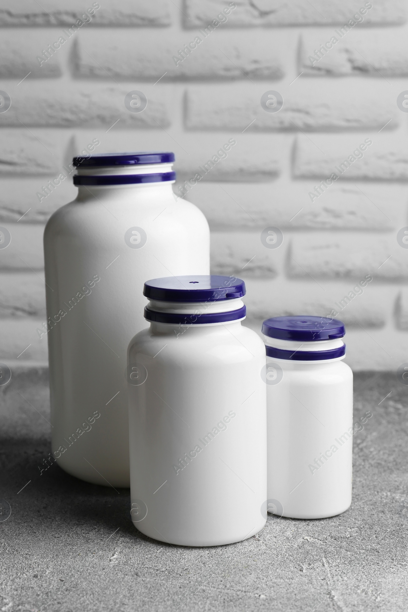 Photo of White medical bottles on light gray textured table