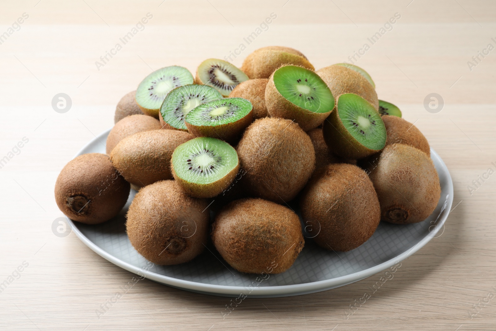 Photo of Fresh ripe kiwis on light wooden table