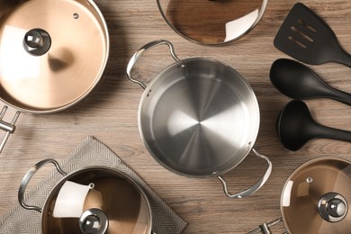 Photo of New cookware set and kitchen utensils on wooden table, flat lay