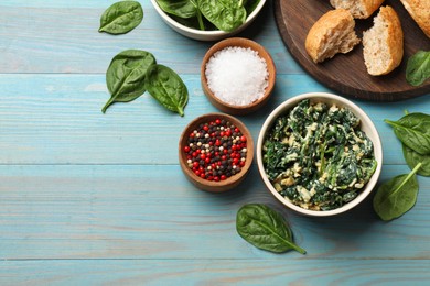 Photo of Tasty spinach dip with egg in bowl, bread and spices on light blue wooden table, flat lay. Space for text