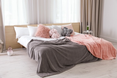 Photo of Comfortable bed with pillows and plaid in modern room interior