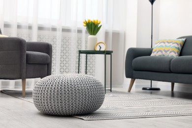 Photo of Spring interior. Grey knitted pouf on floor in living room, space for text