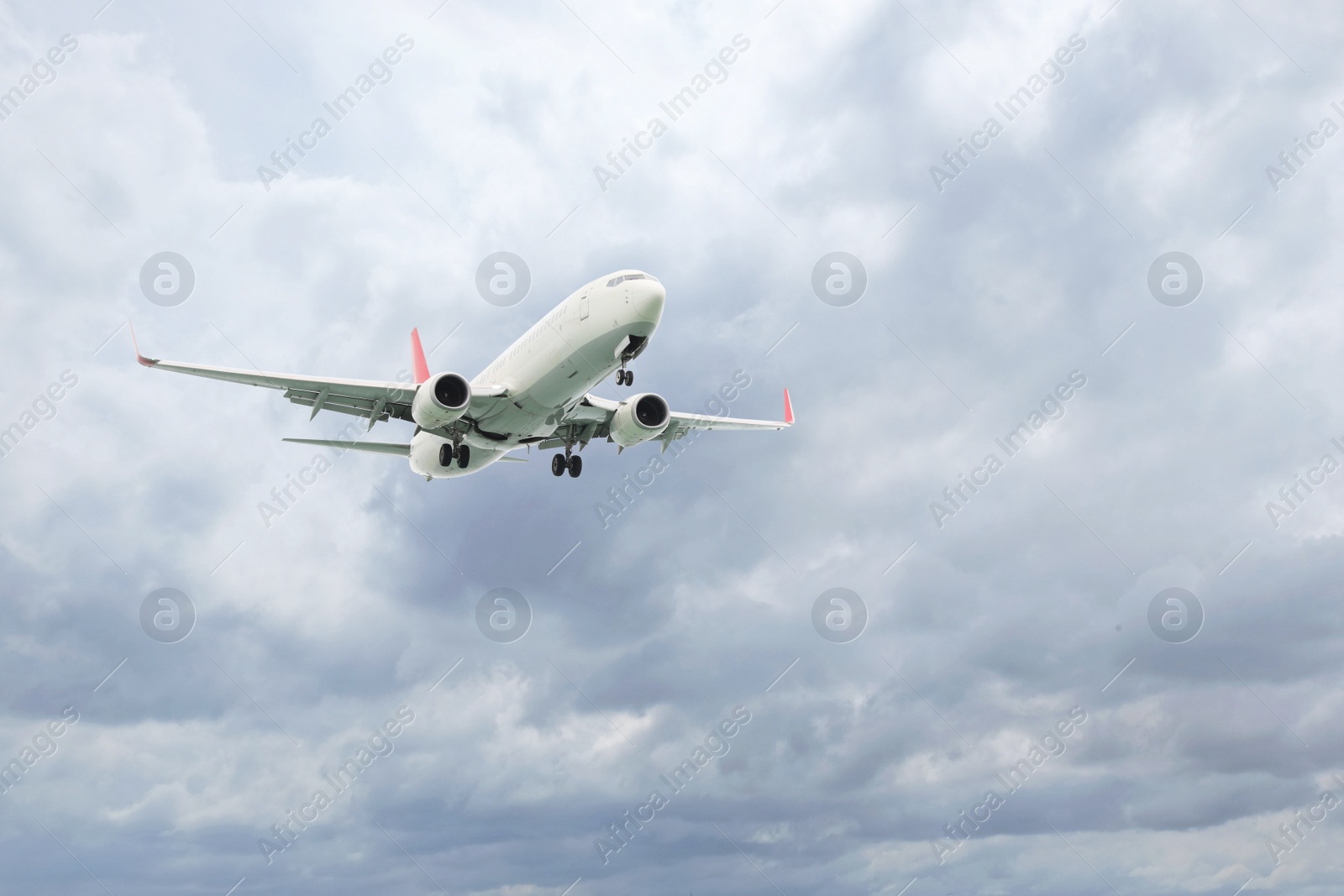 Photo of Airplane flying high in cloudy sky. Modern aircraft