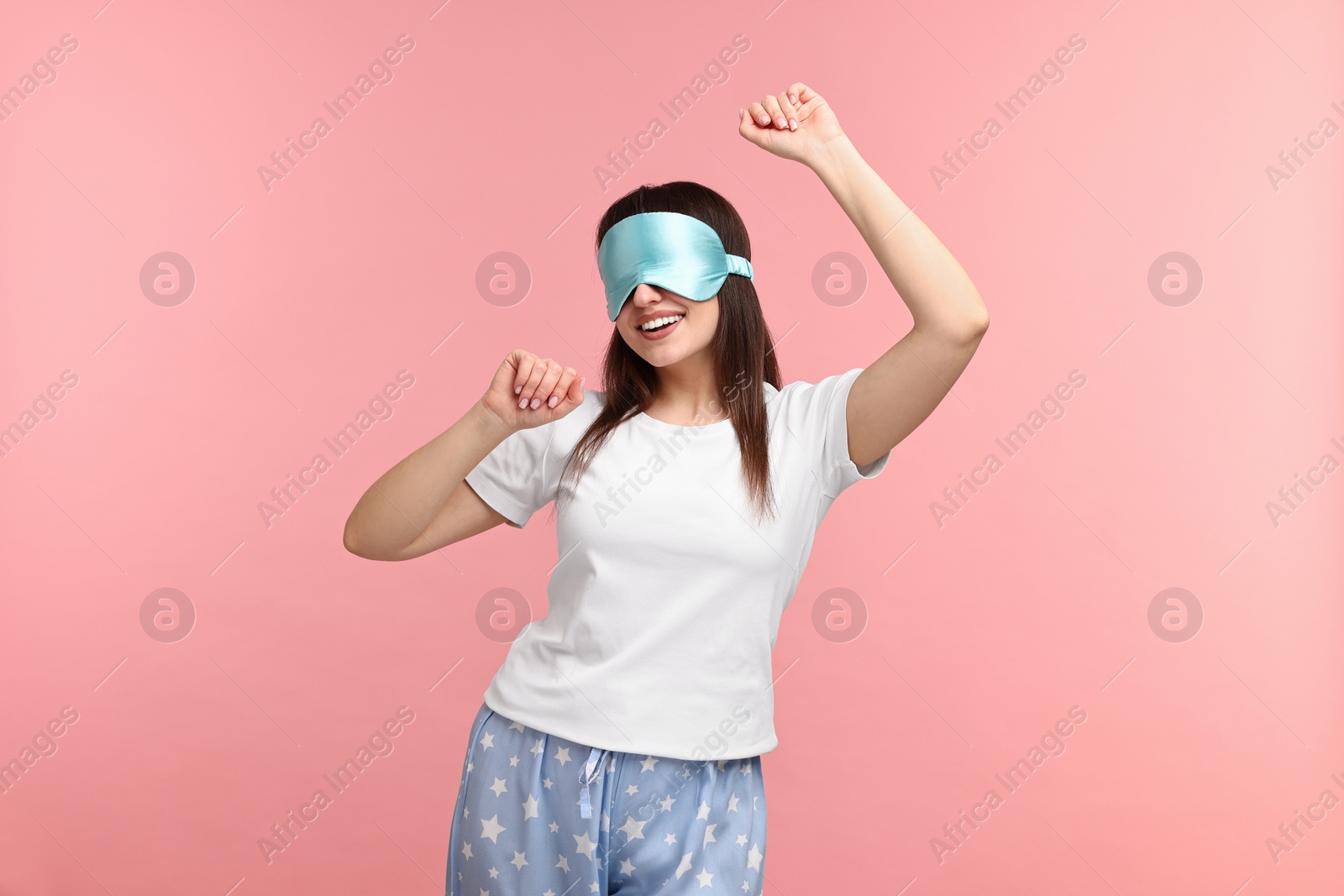 Photo of Happy woman in pyjama and sleep mask on pink background