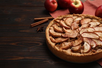 Photo of Delicious apple pie and ingredients on wooden table, space for text
