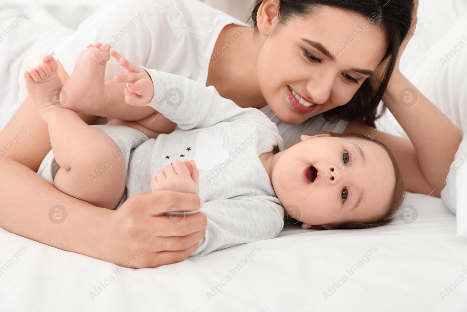 Photo of Cute baby and mother lying on bed