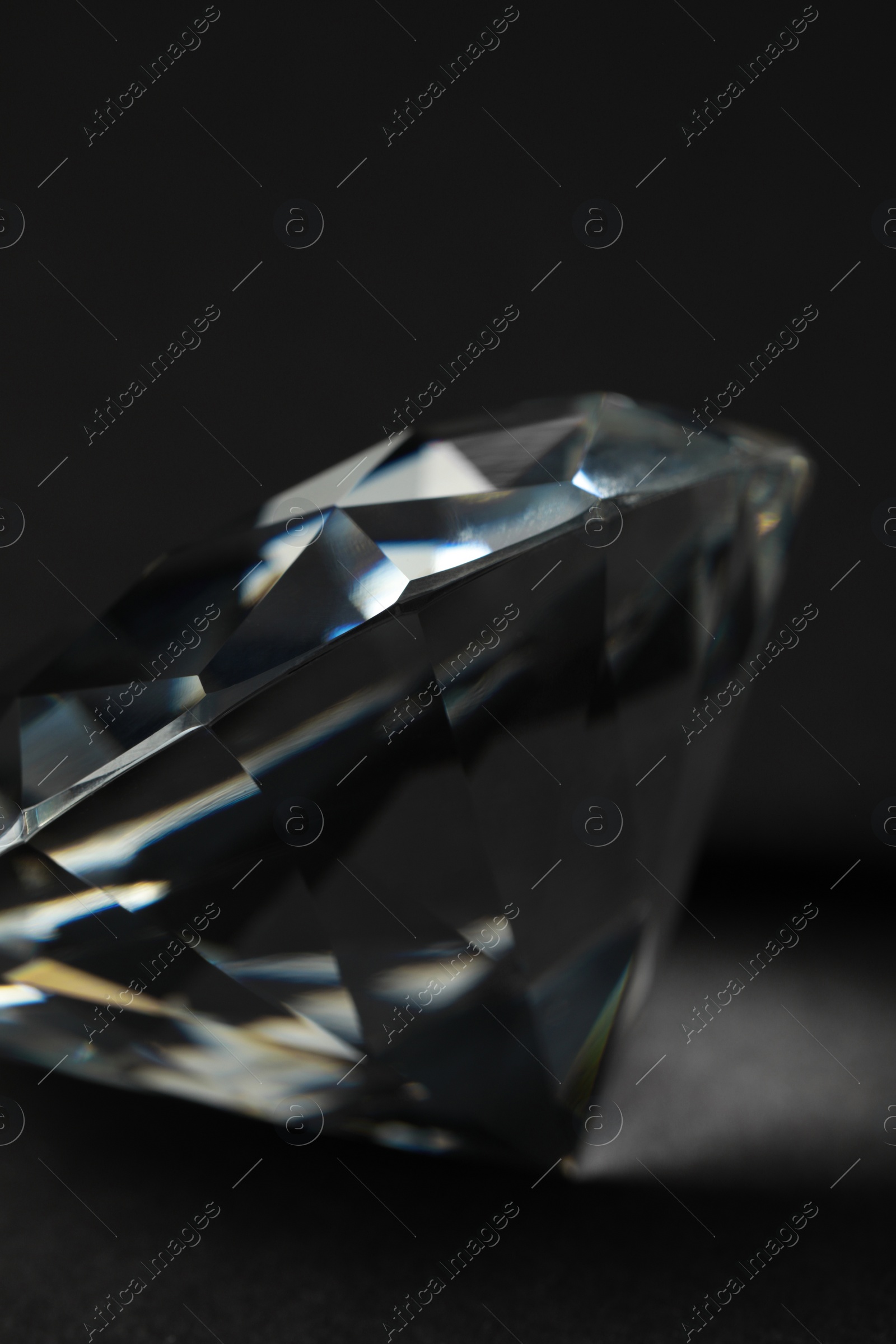 Photo of Beautiful dazzling diamond on dark background, closeup. Precious gemstone