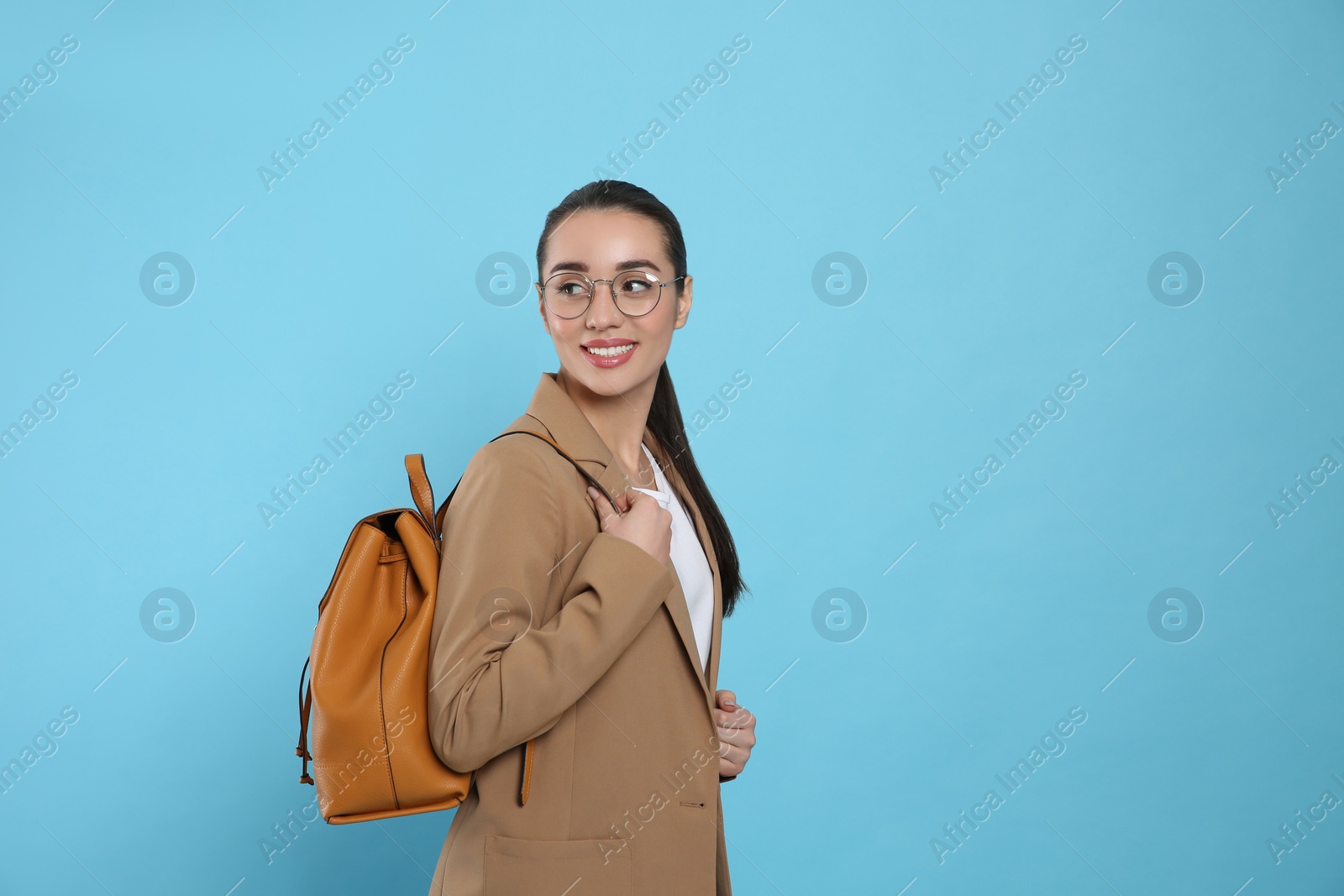 Photo of Beautiful young woman with stylish leather backpack on turquoise background. Space for text