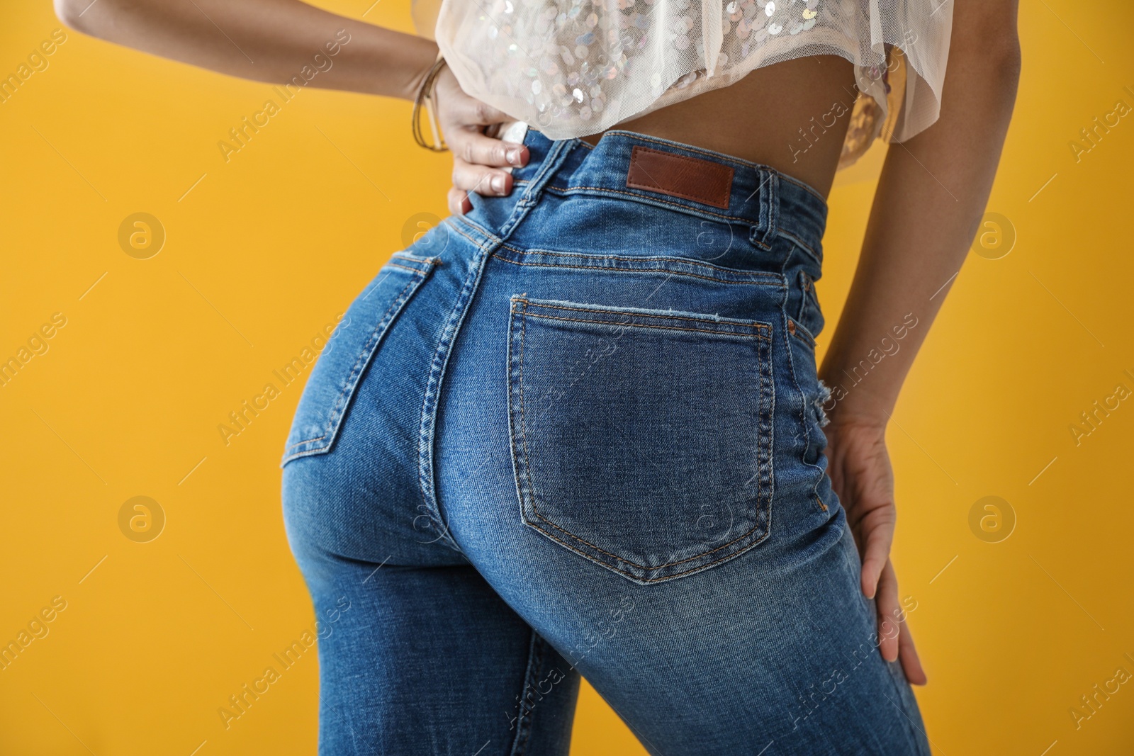 Photo of Woman wearing jeans on yellow background, closeup