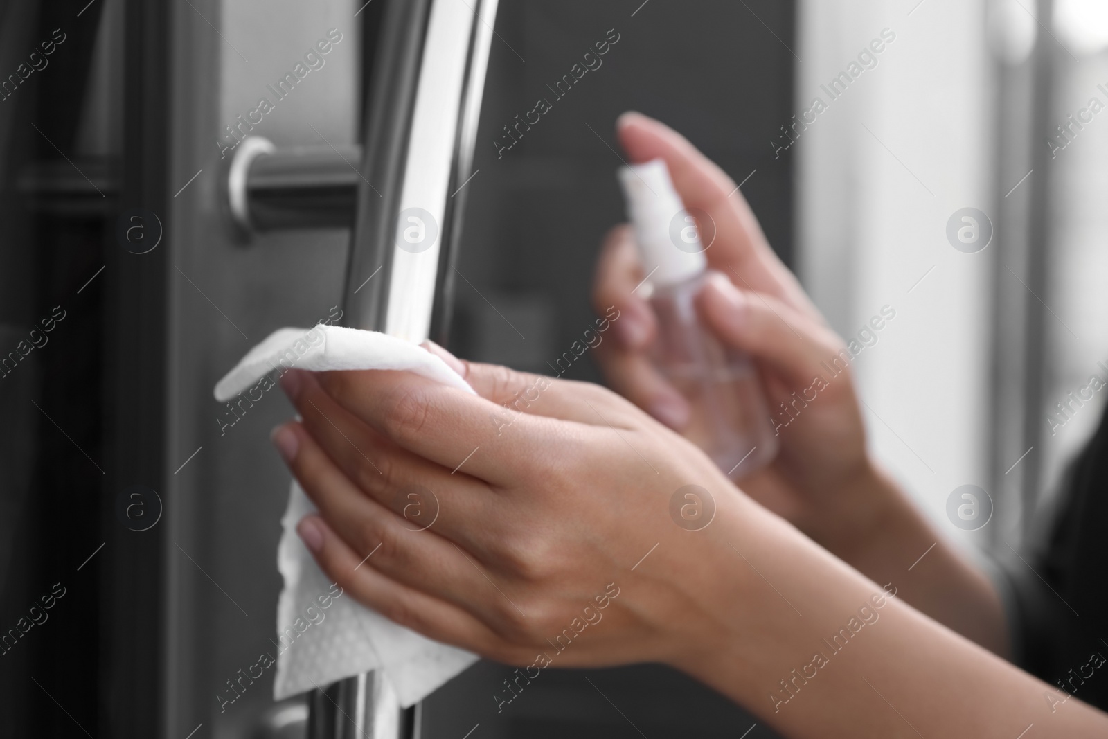 Photo of Woman cleaning door handle with wet wipe outdoors, closeup