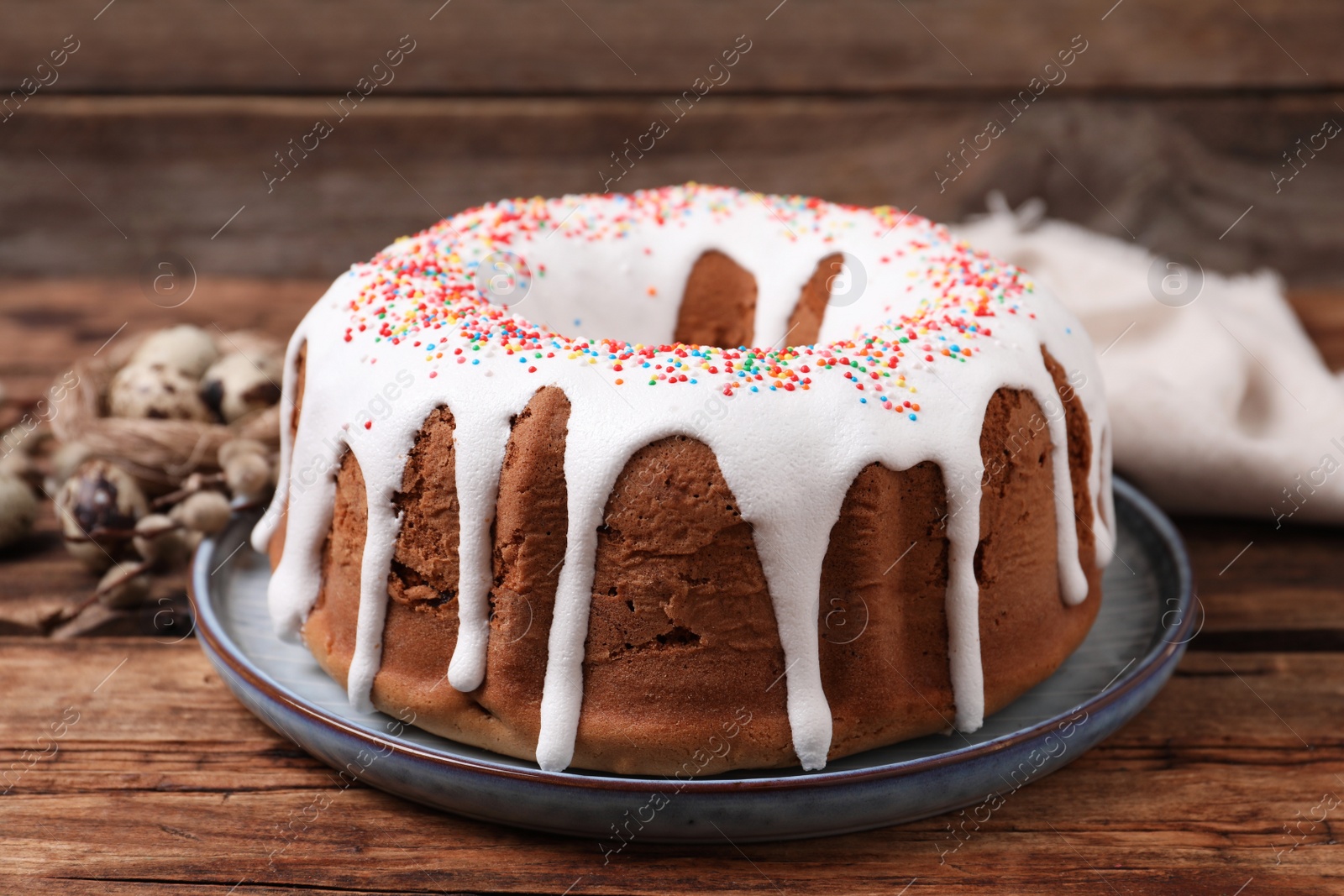 Photo of Glazed Easter cake with sprinkles on wooden table