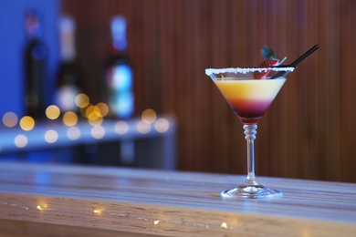 Photo of Delicious strawberry martini cocktail on table in bar, space for text