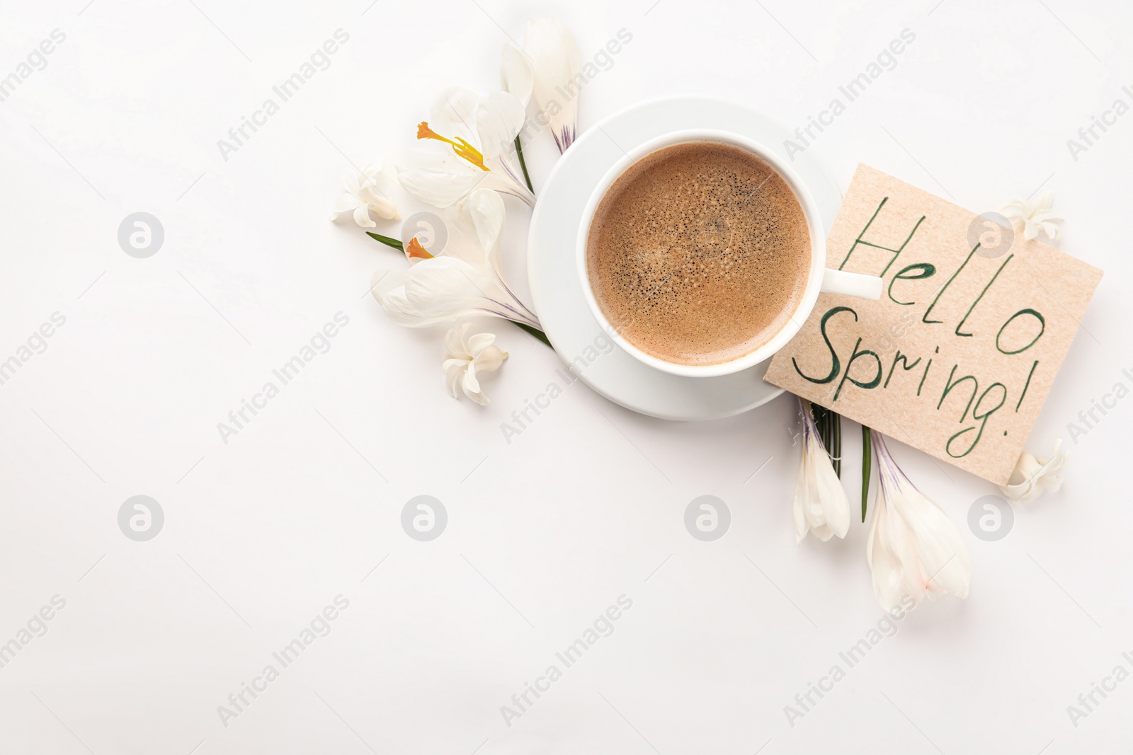 Photo of Card with words HELLO SPRING, cup of coffee and fresh flowers on white background, flat lay. Space for text