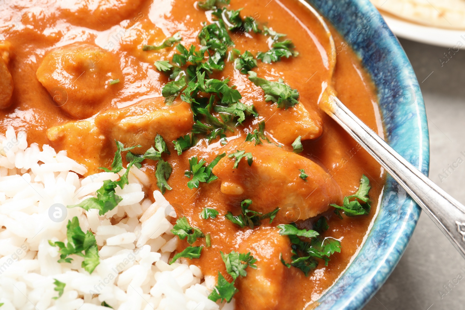 Photo of Delicious butter chicken with rice in bowl on table, closeup