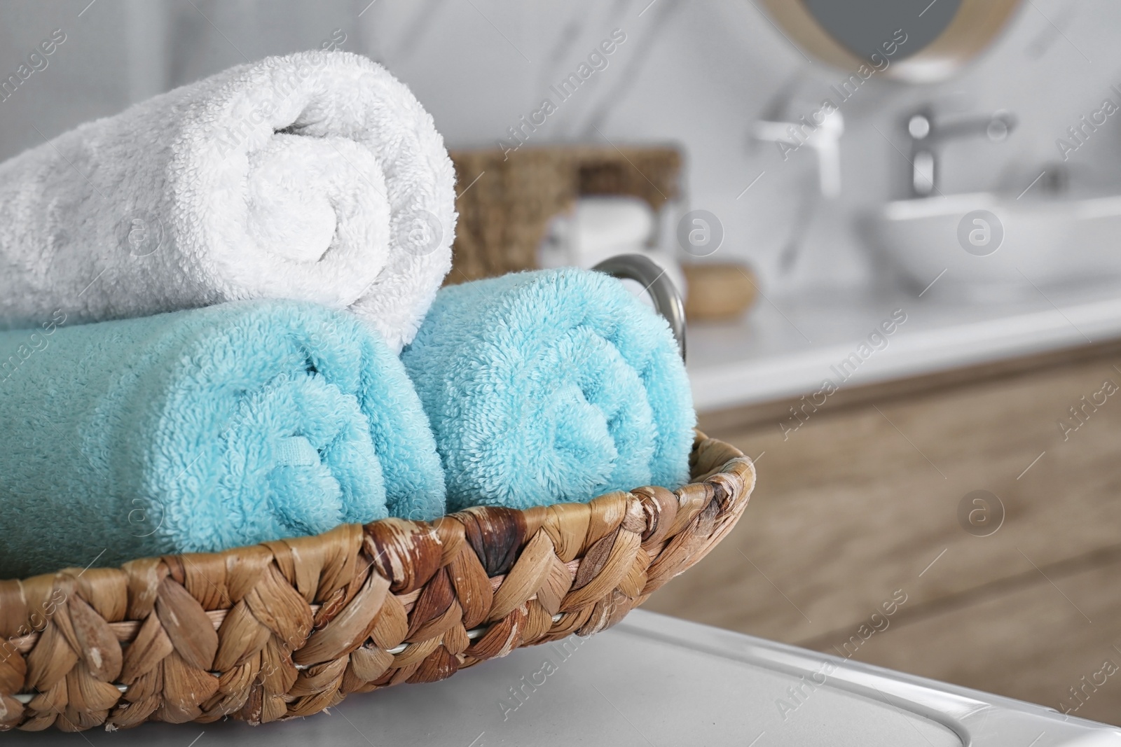 Photo of Wicker tray with clean soft towels in bathroom, closeup