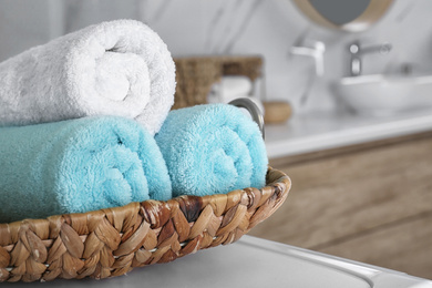 Photo of Wicker tray with clean soft towels in bathroom, closeup