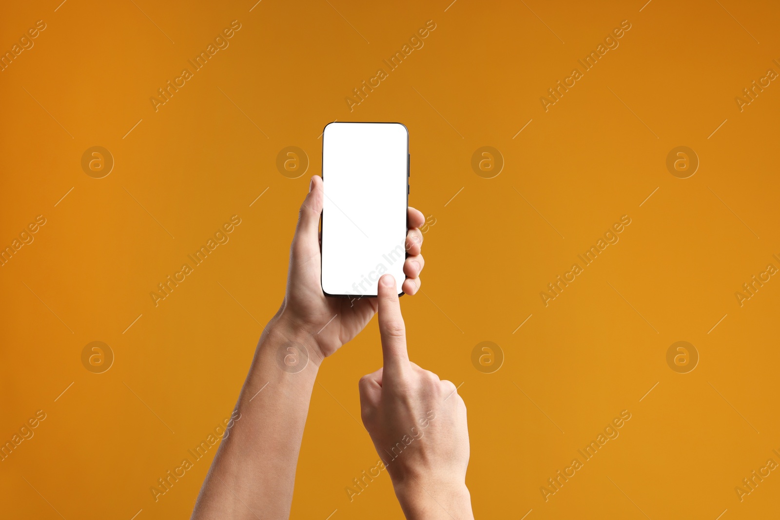 Photo of Man using smartphone with blank screen on orange background, closeup. Mockup for design