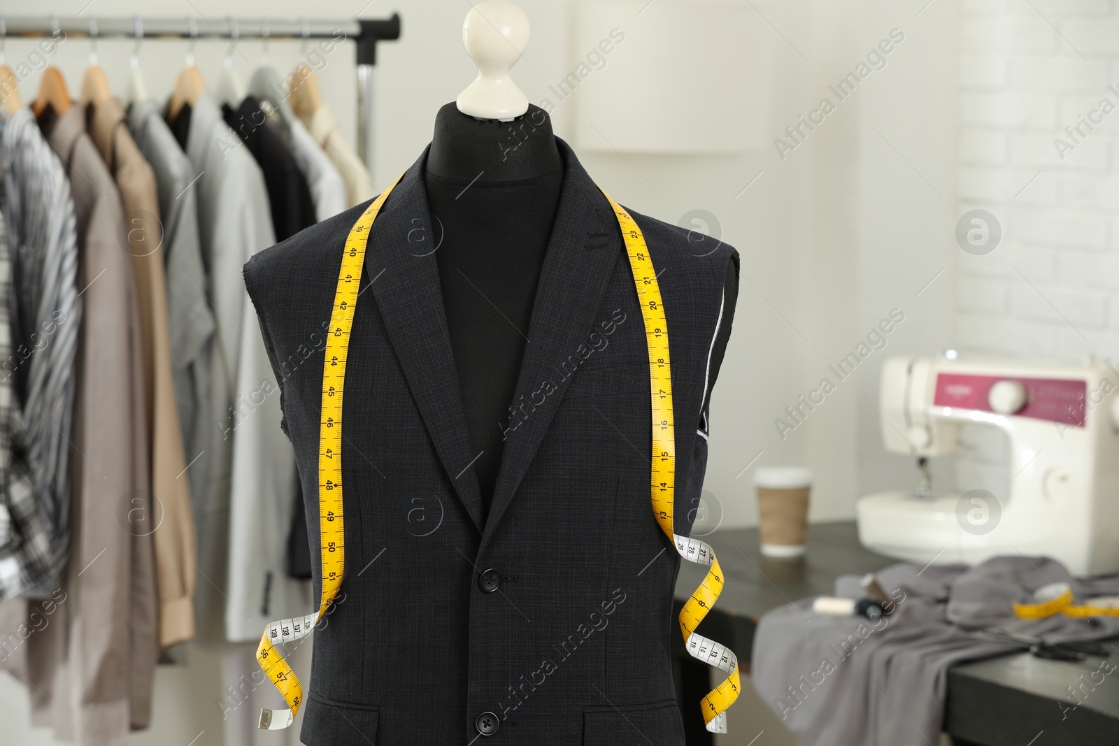 Photo of Mannequin with unfinished jacket and measuring tape in tailor shop