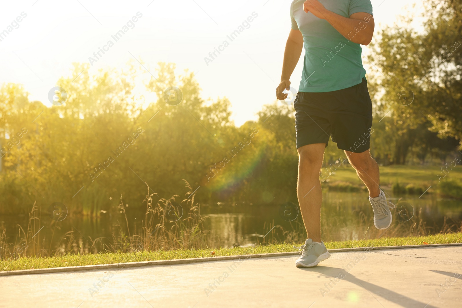 Photo of Man running near pond in park, closeup. Space for text