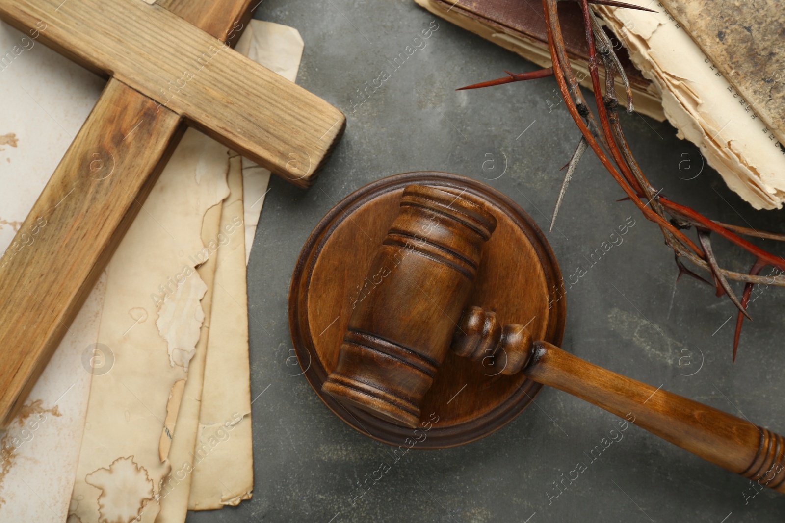 Photo of Judge gavel, wooden cross and crown of thorns on grey table, flat lay