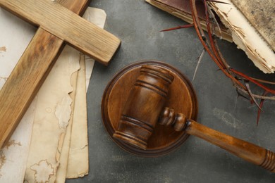 Photo of Judge gavel, wooden cross and crown of thorns on grey table, flat lay