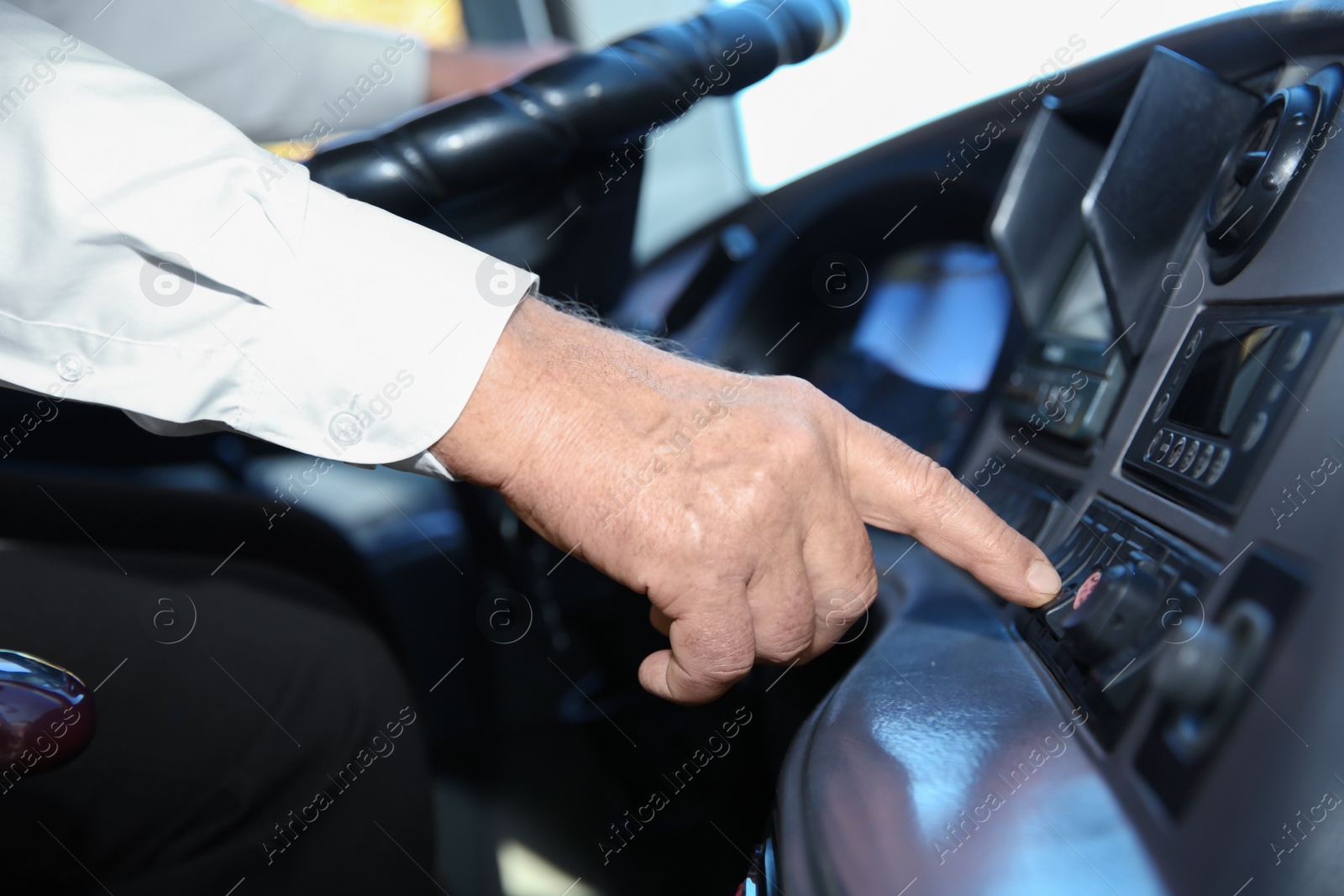 Photo of Professional bus driver pushing button on dashboard. Passenger transportation