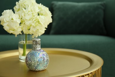 Photo of Stylish catalytic lamp with hydrangea on golden table in living room, space for text. Cozy interior