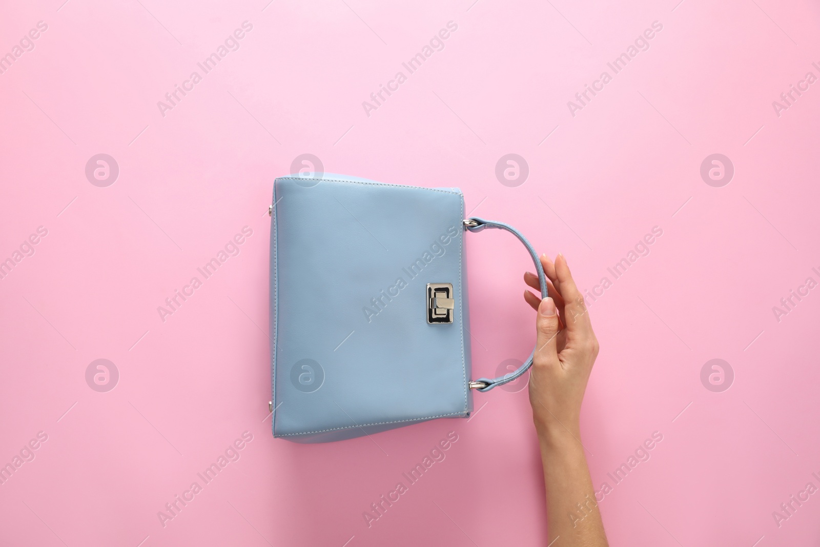 Photo of Woman holding stylish handbag on pink background, closeup
