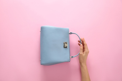 Photo of Woman holding stylish handbag on pink background, closeup