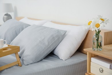 Photo of Bouquet of beautiful daisy flowers on nightstand in bedroom, space for text