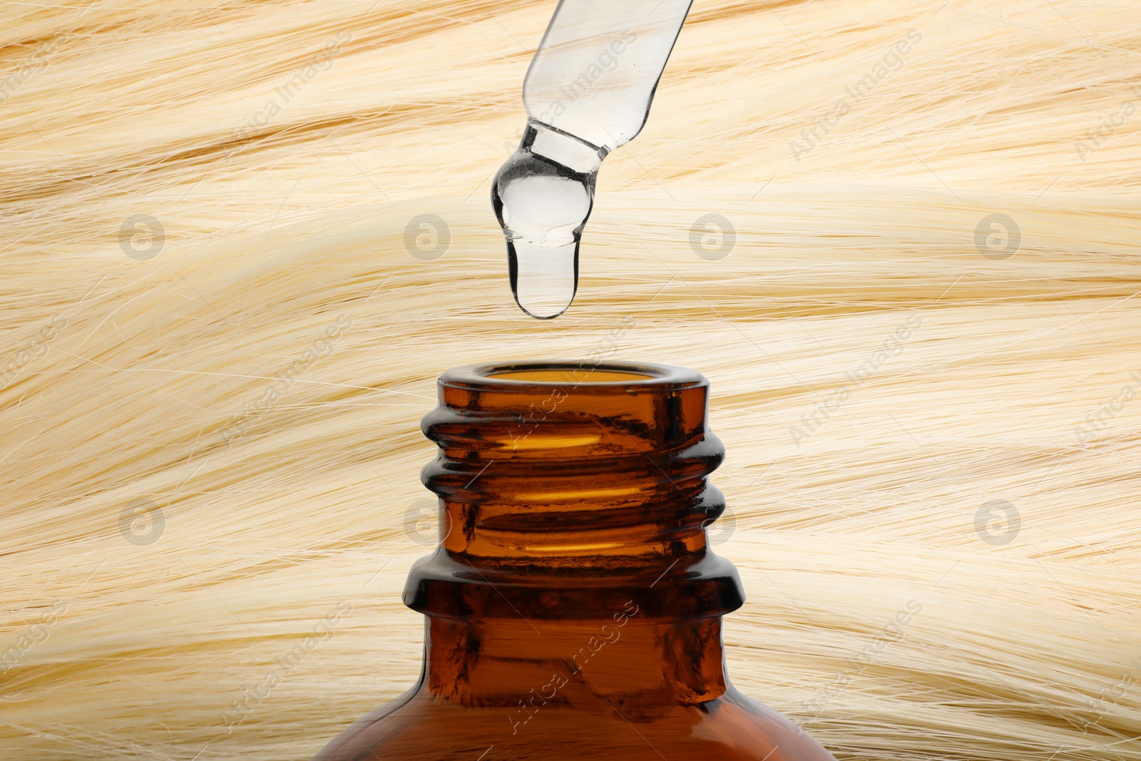 Image of Dripping serum from pipette into bottle against beautiful blonde hair