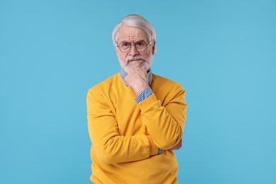 Photo of Portrait of stylish grandpa with glasses on light blue background