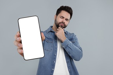 Man holding smartphone with empty screen on grey background