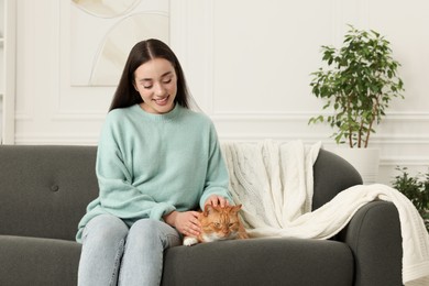 Photo of Beautiful woman petting cute cat on sofa at home