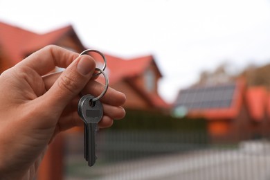 Real estate agent holding keys to new house outdoors, closeup. Space for text