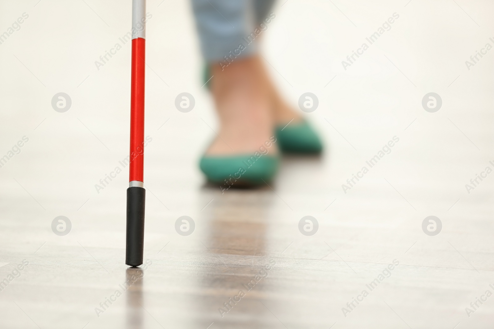 Photo of Blind person with long cane walking indoors, closeup