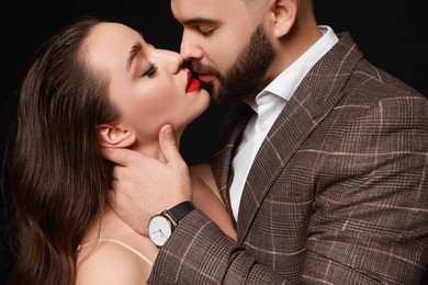 Photo of Handsome bearded man with sexy lady on black background, closeup