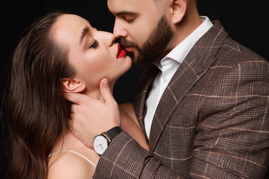 Handsome bearded man with sexy lady on black background, closeup