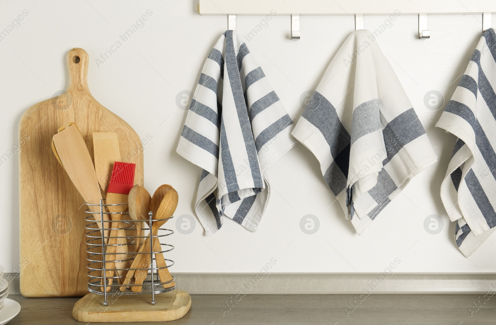 Photo of Different kitchen towels hanging on hook rack indoors