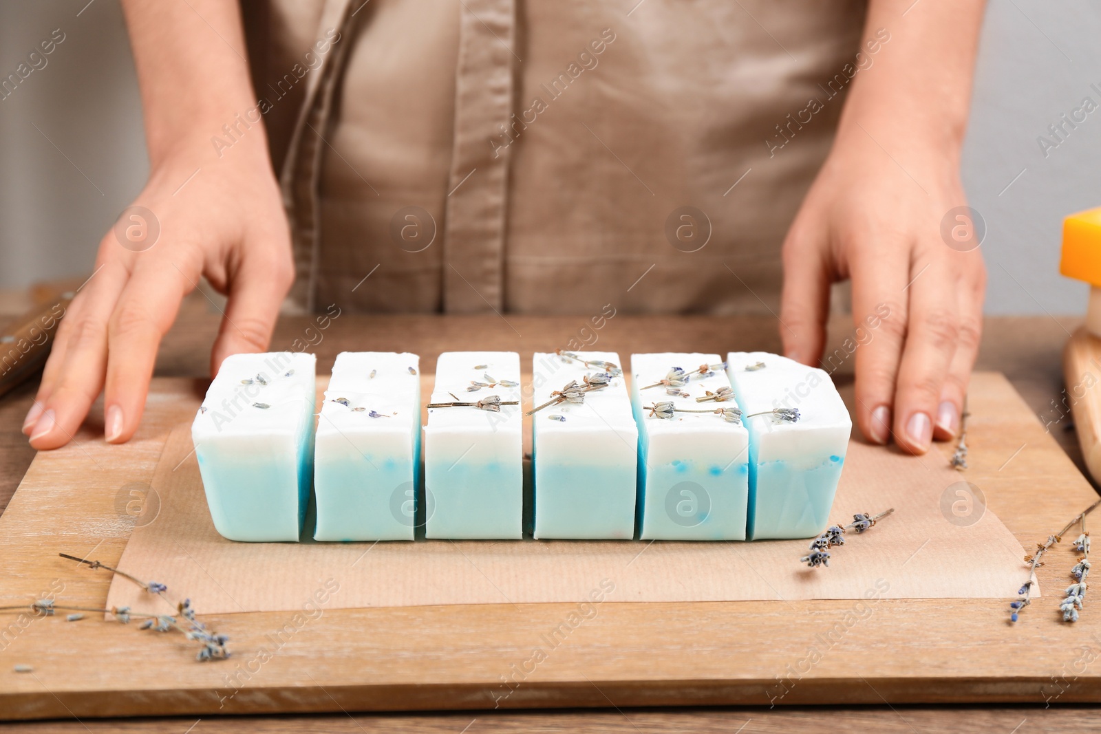 Photo of Woman with natural handmade soap at wooden table, closeup